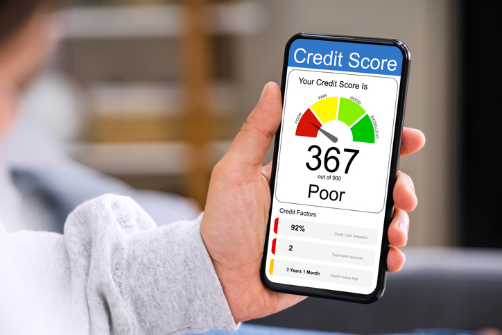 Person holding phone which shows poor credit score of 367
